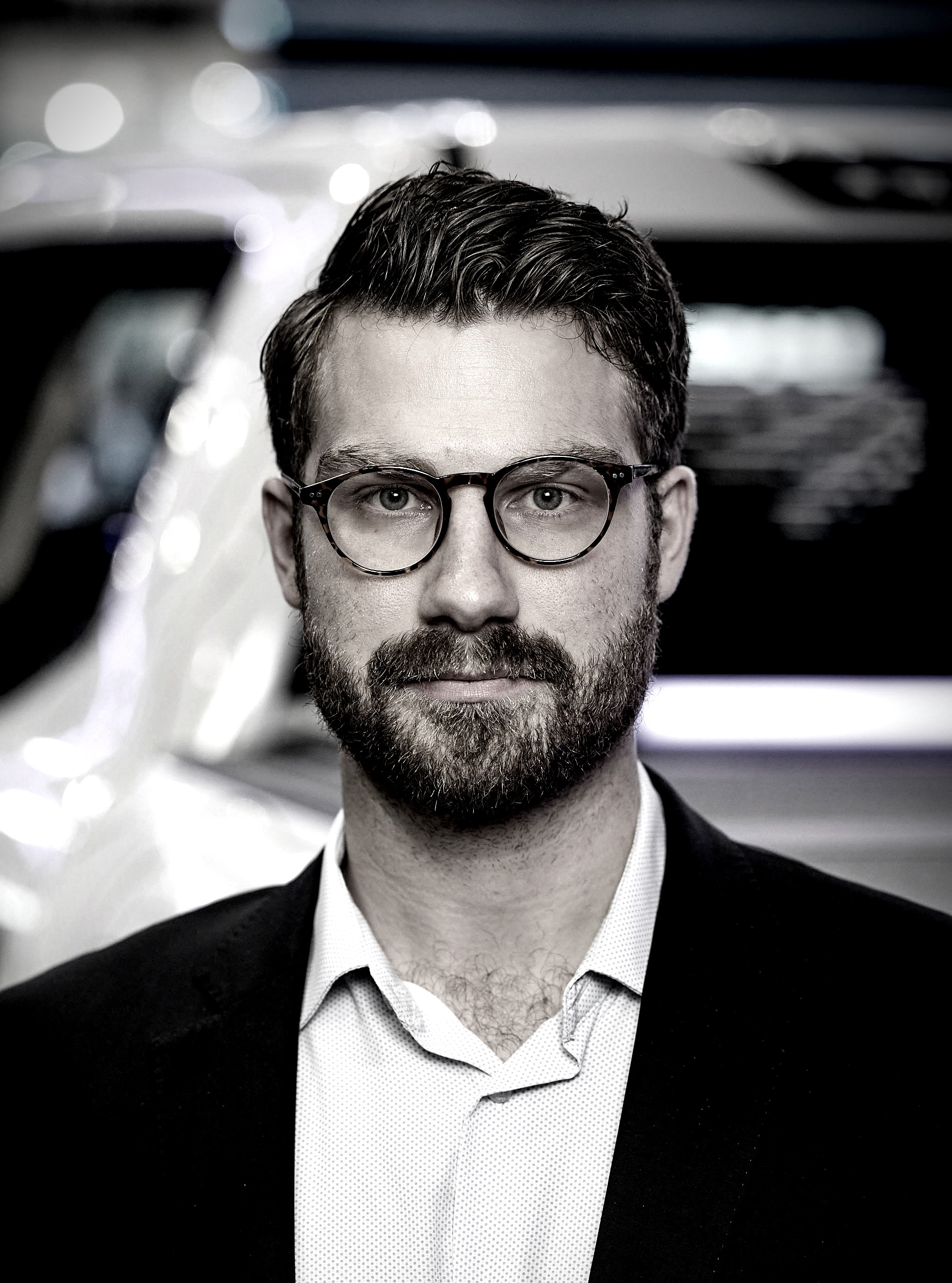 Black-and-white headshot of Jake Headman in a blazer and glasses